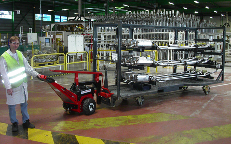 Power Pusher, with Steering Arm, moving trolley loaded with automotive exhaust assemblies at Faurecia, France Power Pusher, with Steering Arm, moving trolley loaded with automotive exhaust assemblies at Faurecia, France